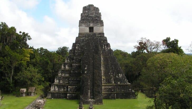 Ancient Maya pyramid in Tikal surrounded by dense greenery showcasing architectural grandeur