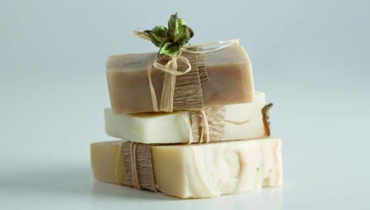 Three stacked bars of soap wrapped with twine and a decorative plant accent